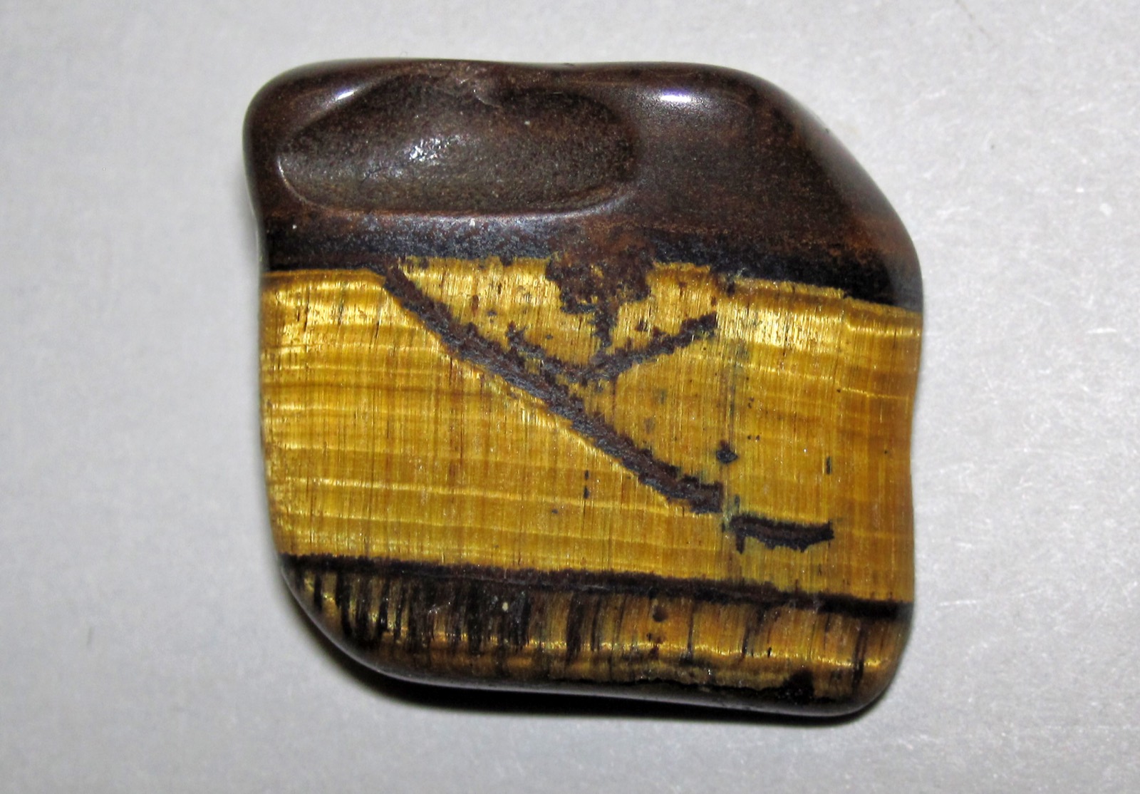 Polished tiger’s eye with tightly packed golden fibres and a moving band of light
